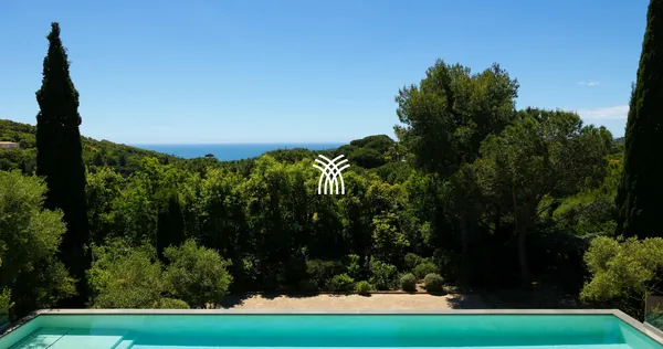 The long pool of Villa Texas in Ramatuelle, lined with cypresses, with a glimpse of the sea.
